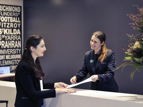 two women are shaking hands at a table at Mercure North Melbourne in Melbourne