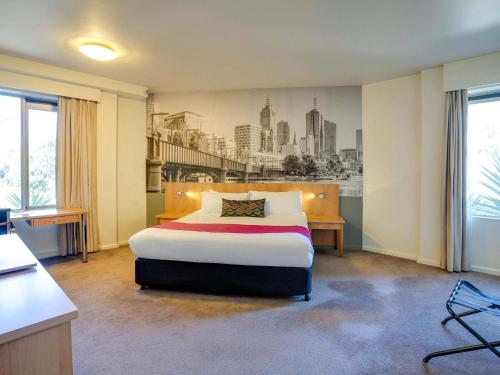a bedroom with a bed with a city mural on the wall at Mercure North Melbourne in Melbourne