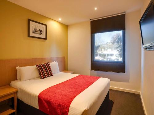 a small bedroom with a bed and a window at Mercure North Melbourne in Melbourne