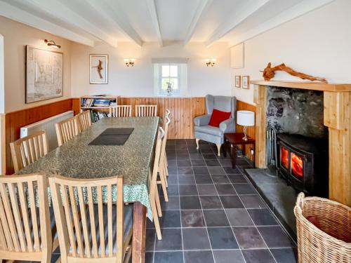 a dining room with a table and chairs and a fireplace at Kirklandbank Farmhouse in Alyth