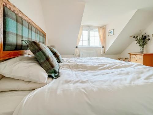 a bedroom with a large white bed with pillows at Kirklandbank Farmhouse in Alyth