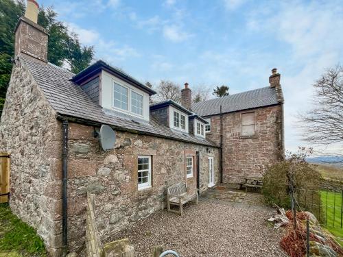 an old stone house with a bench in front of it at Kirklandbank Farmhouse in Alyth