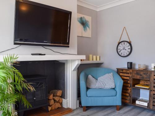 a living room with a blue chair and a tv above a fireplace at Pleasant Place in Kegworth
