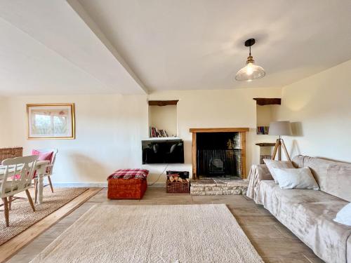 a living room with a couch and a fireplace at Drovers Cottage in Tetbury