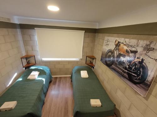 una habitación con 2 camas y una foto de una motocicleta en la pared en Cyclotel Motoposada, en Valle Hermoso