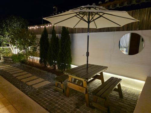 a picnic table with an umbrella and a bench at Hyu Stay in Gyeongju