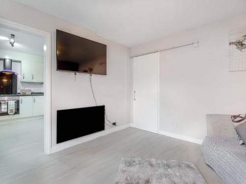Una sala de estar blanca con un televisor y un sofá. en Failte Luxury Apartment, en Inverness