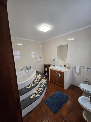 a bathroom with a tub and a sink at Lagoa Fabulous House in Lagoa