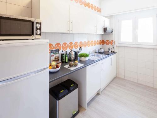 a white kitchen with a sink and a refrigerator at Aparthotel Adagio Rome Vatican in Rome