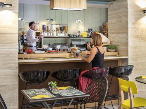 a man and a woman preparing food in a kitchen at Aparthotel Adagio Rome Vatican in Rome