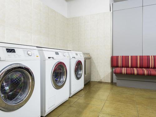 a laundry room with two washing machines and a red bench at Aparthotel Adagio Rome Vatican in Rome