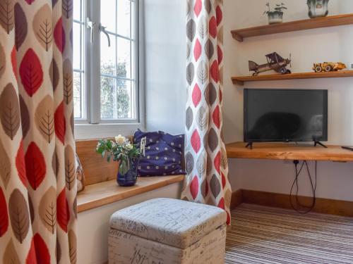a living room with a television and a ottoman at Pickled Onion Cottage in Taunton