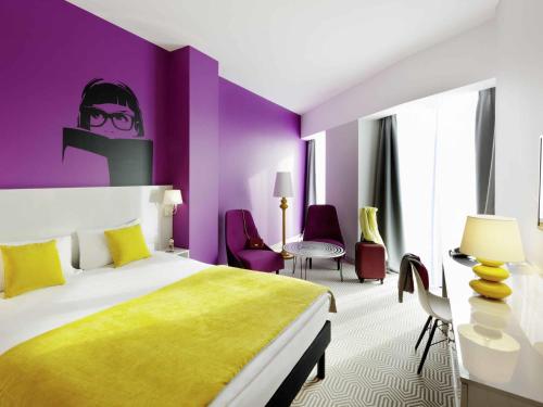 a hotel room with a bed and a purple wall at Ibis Styles Wroclaw Centrum in Wrocław