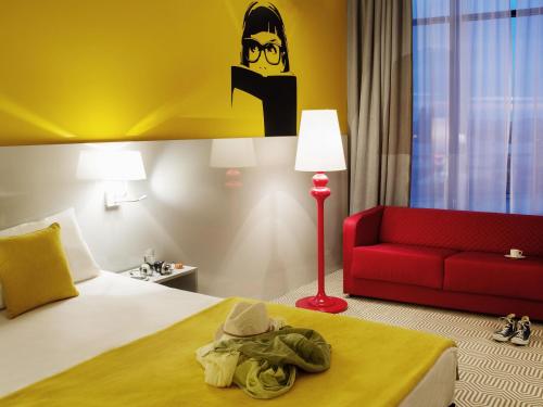 a hotel room with a bed and a red couch at Ibis Styles Wroclaw Centrum in Wrocław