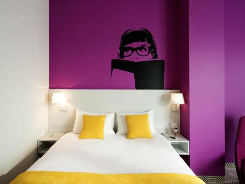 a bedroom with a bed with a purple wall at Ibis Styles Wroclaw Centrum in Wrocław