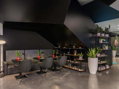 a restaurant with black walls and chairs and plants at Ibis Styles Wroclaw Centrum in Wrocław