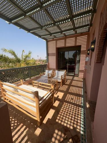 a patio with wooden benches on a building at Appartement standing piscine la palmeraie in Marrakech