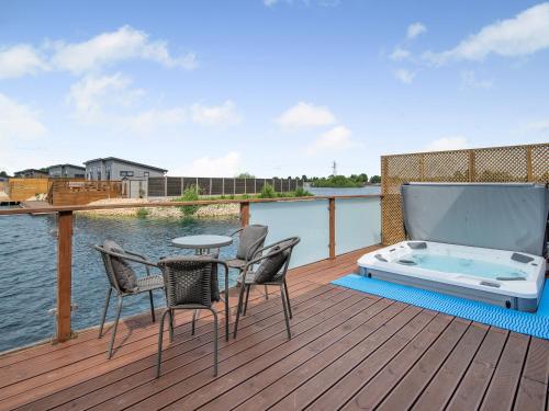 a deck with a hot tub and chairs on the water at Lakeside Lodge in Barholm