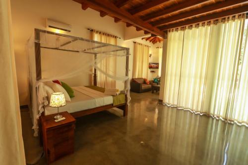 a bedroom with a canopy bed and a living room at Beach Grove Villas in Unawatuna
