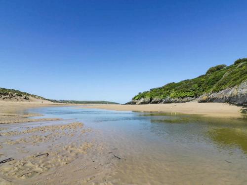 a beach with a body of water next to a hill at 82 Hillside in Newquay