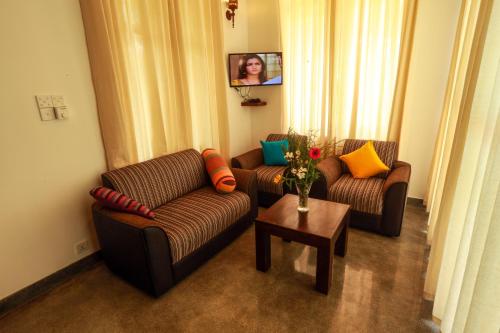 a living room with two couches and a table at Beach Grove Villas in Unawatuna