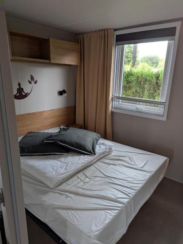 a bed in a small room with a window at Camping les charmettes in Les Mathes