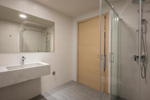 a bathroom with a sink and a glass shower door at Trianon Luxury Apartments & Suites in Chania Town