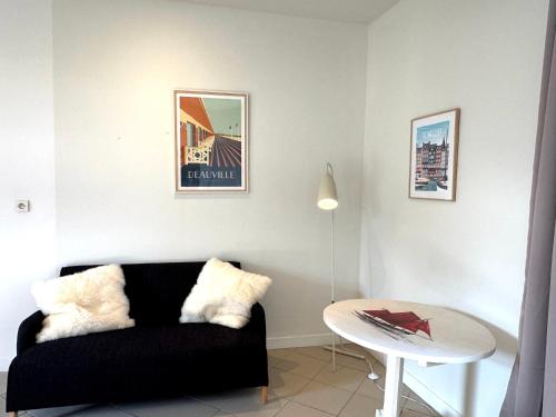 a living room with a black couch and a table at La Maison de Charme, 8-9p, idéale Amis et Familles in Sévigny