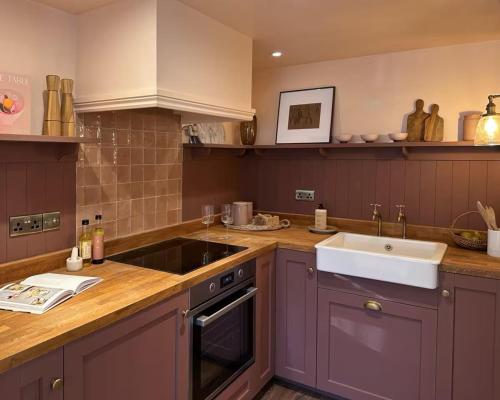 a kitchen with purple cabinets and a sink at Boutique Cottage in the Heart of Kintbury in Kintbury