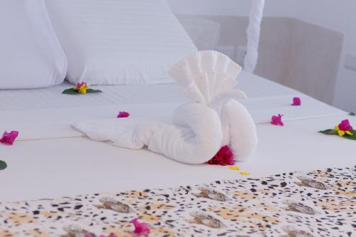a white towel angel on a bed with flowers at Leopard House in Watamu