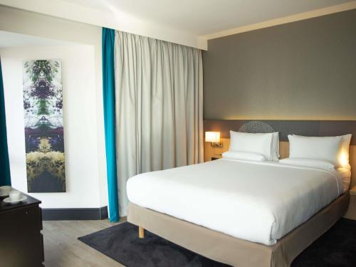 a bedroom with a large white bed and a window at Novotel London Wembley in London