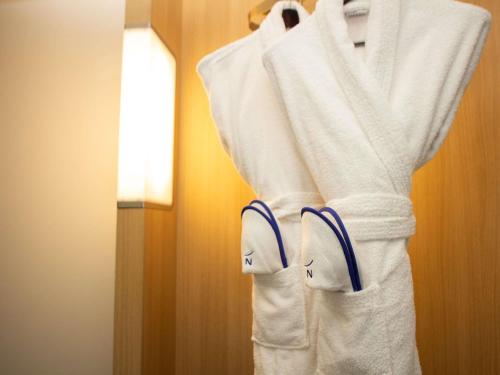 a white robe hanging in a hotel room at Novotel London Wembley in London