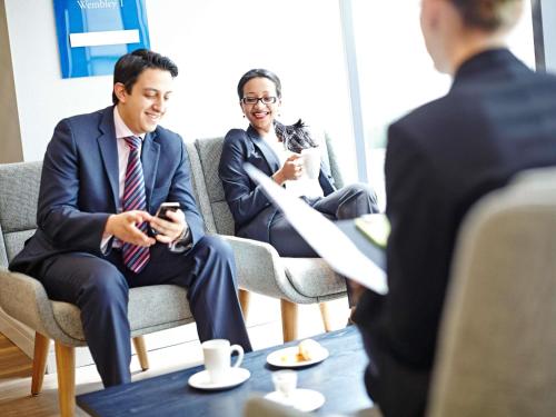 two men and a woman sitting in chairs in a meeting at Novotel London Wembley in London