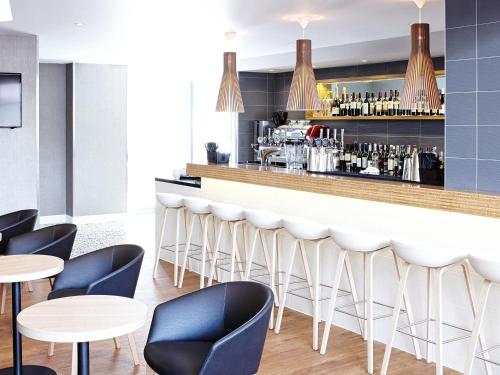 a bar in a restaurant with blue chairs and tables at Novotel London Wembley in London