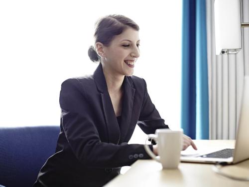 a woman sitting at a desk with a laptop computer at Novotel London Wembley in London