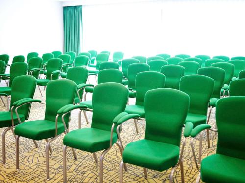 a row of chairs with green chairs in a room at Novotel London Wembley in London