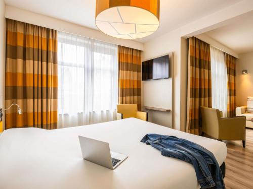 a room with a bed with a laptop on a table at ibis Styles Hotel Brussels Centre Stéphanie in Brussels