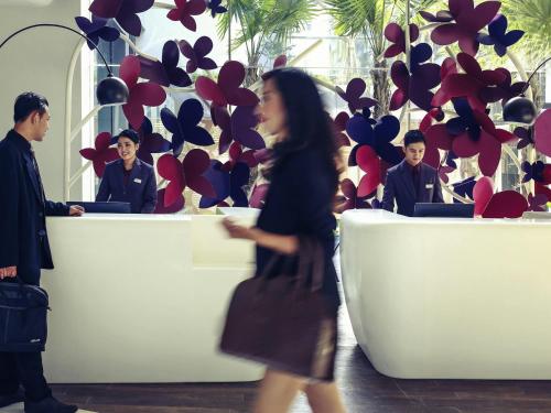 a woman walking in front of a desk with people at Mercure Jakarta Sabang in Jakarta