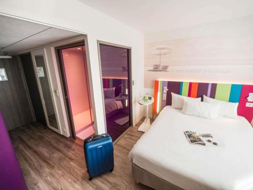 a hotel room with a bed and a suitcase at ibis Styles Les Sables Olonne in Les Sables-dʼOlonne