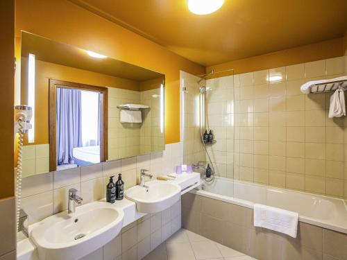 a bathroom with two sinks and a tub and a mirror at Mercure Riga Centre in Rīga