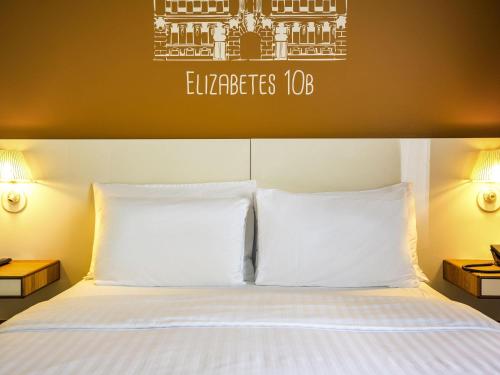 a hotel room with a bed with white pillows at Mercure Riga Centre in Rīga