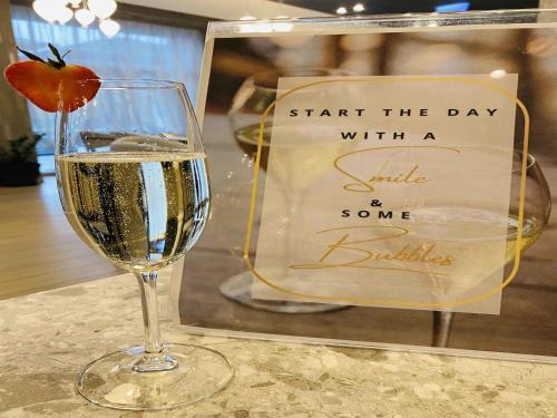 a glass of wine sitting on a table with a sign at Mercure Riga Centre in Rīga