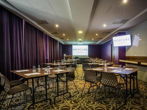 a dining room with tables and chairs and two screens at Mercure Riga Centre in Rīga