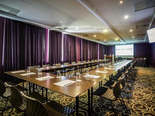 a row of tables in a room with purple curtains at Mercure Riga Centre in Rīga