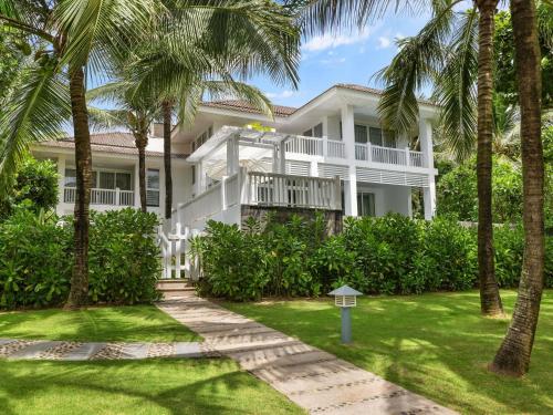 a white house with palm trees in front of it at Premier Village Danang Resort Managed By Accor in Da Nang