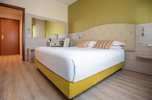 a bedroom with a large white bed and a desk at Hotel Castello Artemide Congressi in Castel San Pietro Terme