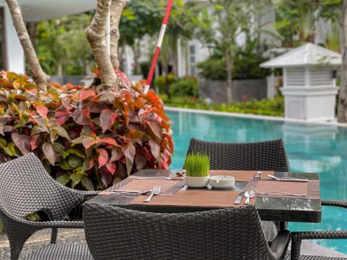 an outdoor table with chairs and a swimming pool at Premier Village Danang Resort Managed By Accor in Da Nang