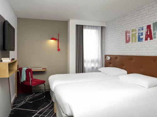 a hotel room with a bed and a red chair at ibis Styles Chartres Métropole in Chartres