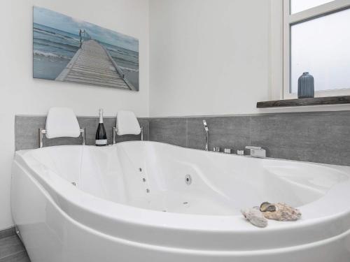 a white bath tub in a bathroom with a painting at 10 person holiday home in Jerup in Jerup