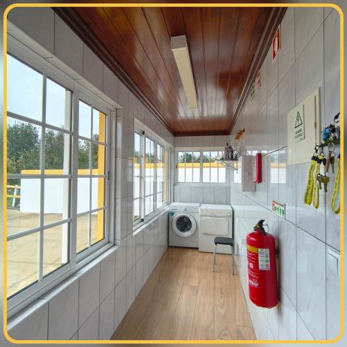 a laundry room with a washing machine and windows at Herdade das Hortênsias in Santo Antão